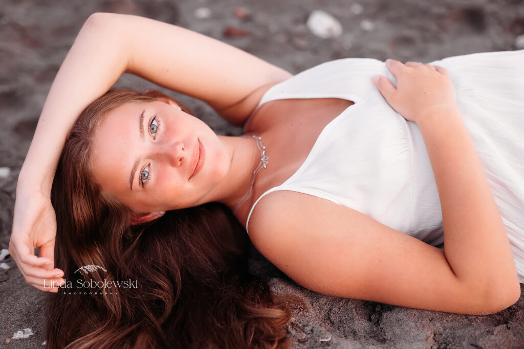 beautiful girl in white dress laying in the sand at the beach, CT best senior photographer