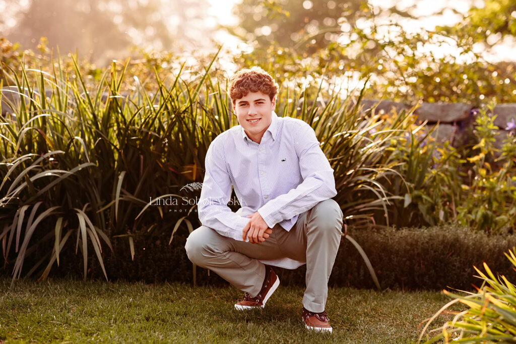 boy squatting in front of bushes, CT senior portrait session