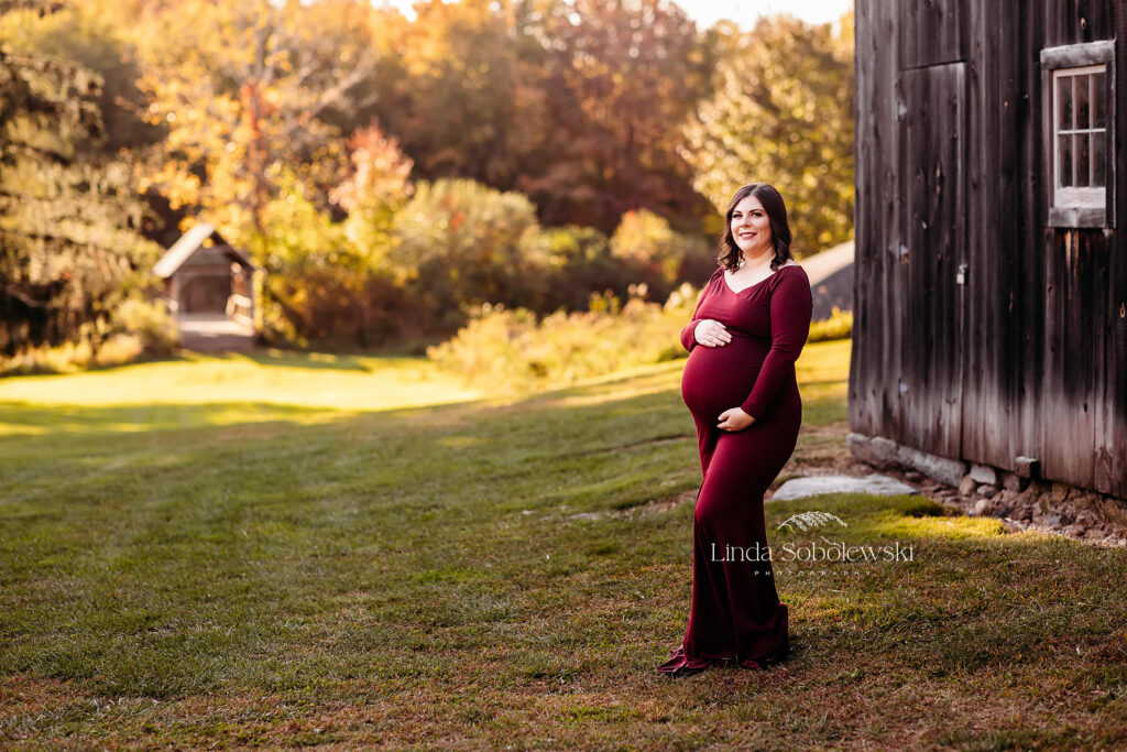 pregnant woman in red dress in a field for a maternity photoshoot in CT