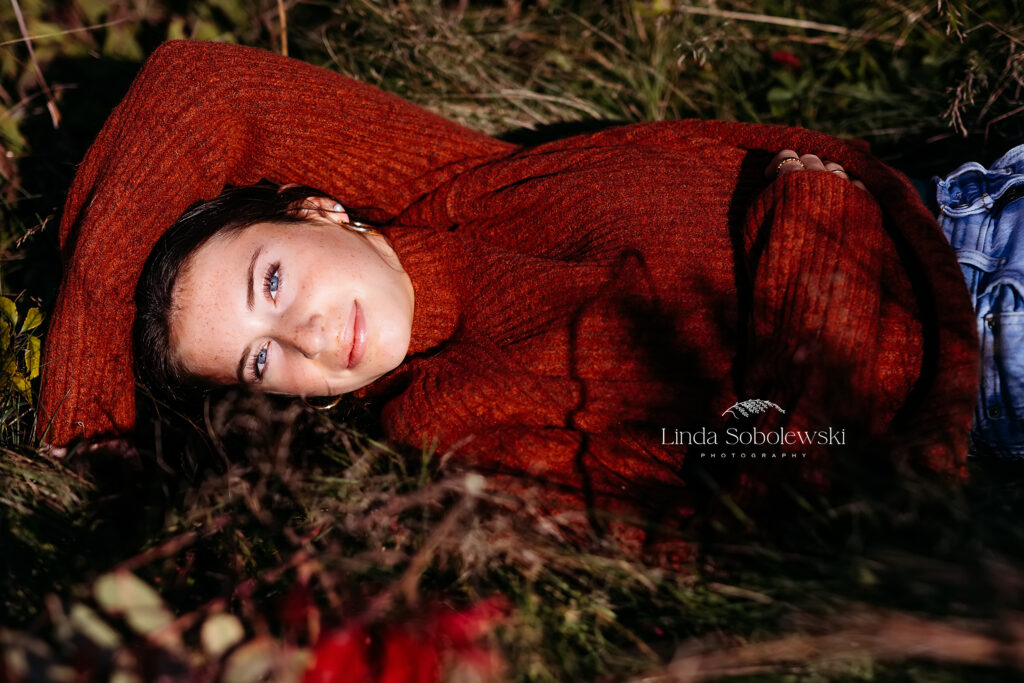 girl in red sweater laying in a field, Old Saybrook CT senior photographer