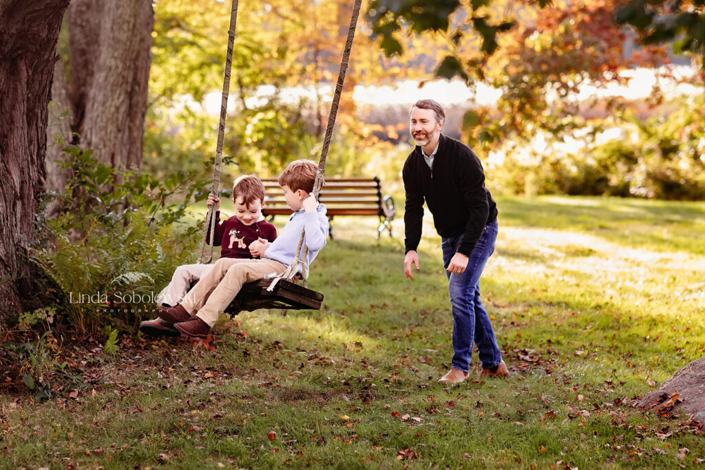 father pushing his young sons on a swing, CT shoreline senior and family photographer