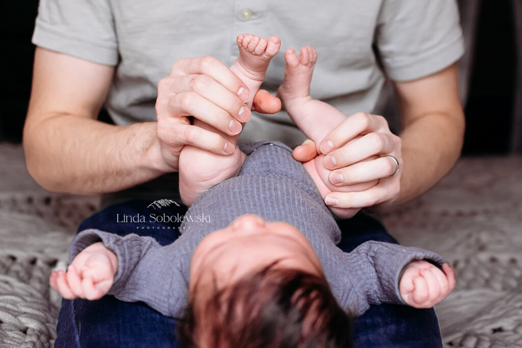 newborn baby laying in father's lap,