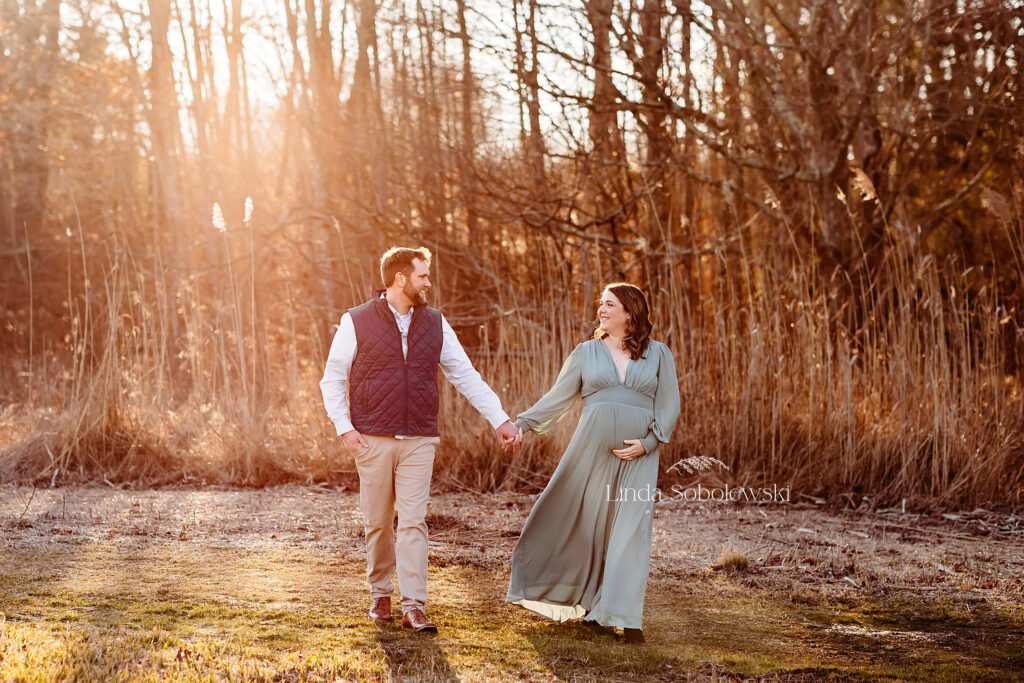 expectant mother and her husband walking in a field, Winter maternity photos in CT