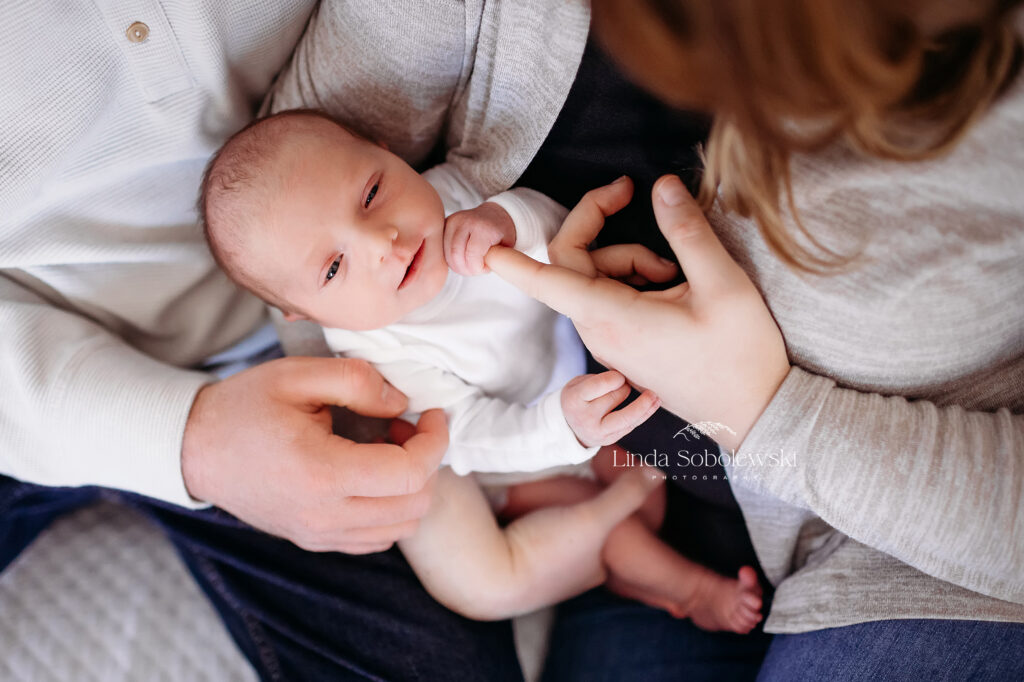 baby in white t-shirt holding her mom's finger, CT Newborn photograper