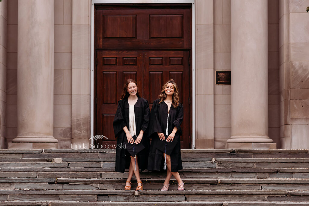two girls in black graduation robes standing on the steps, CT senior photographer