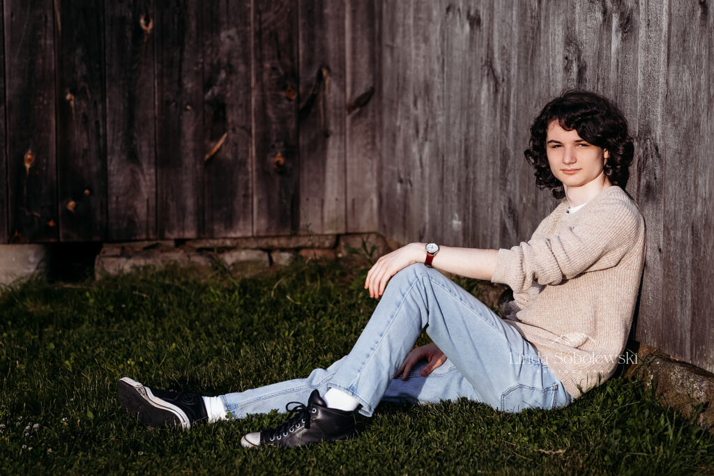 teenage boy with black hair leaning against a wooden wall, Senior boy session in Madison, CT