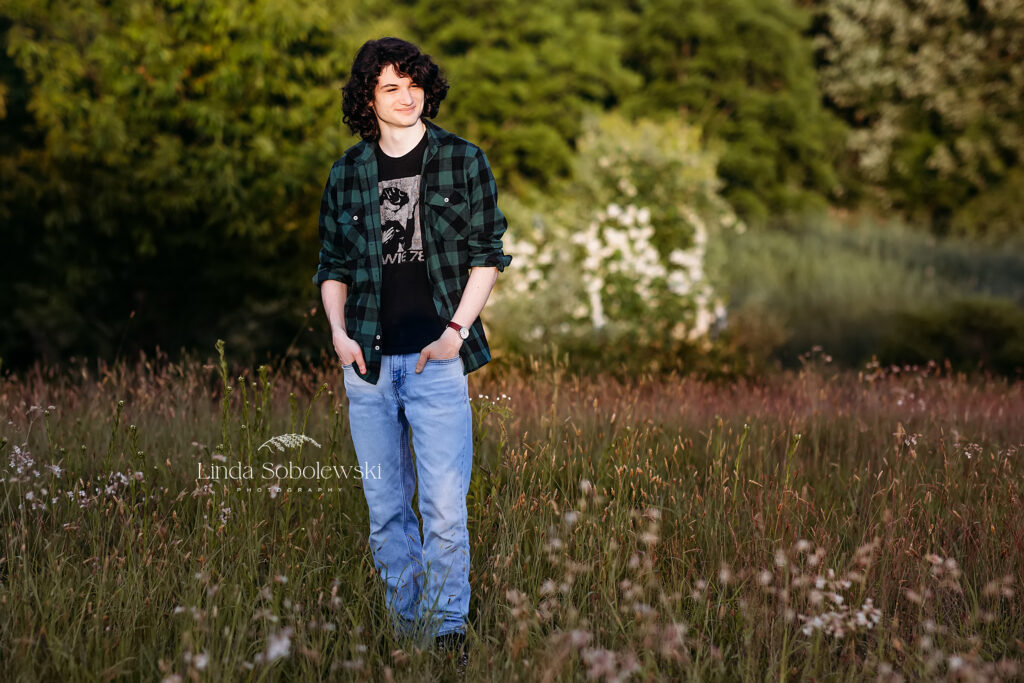 teenage boy with black hair standing in a field of wildflowers, Senior Photo session in Madison, CT