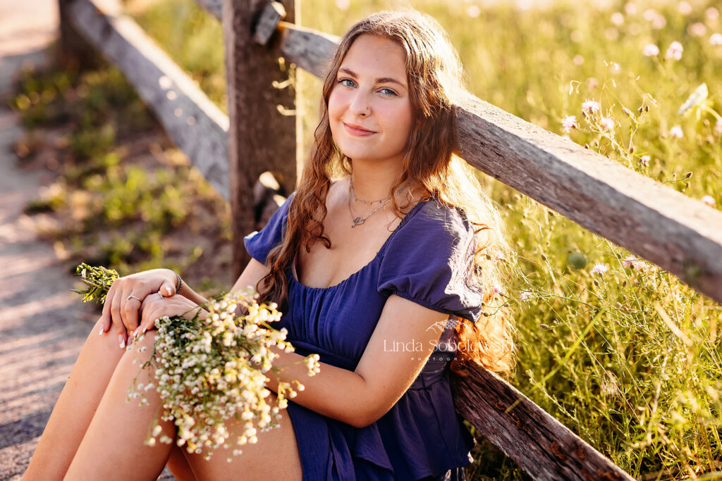 girl in blue dress leaning against a fence. CT shoreline senior photographer