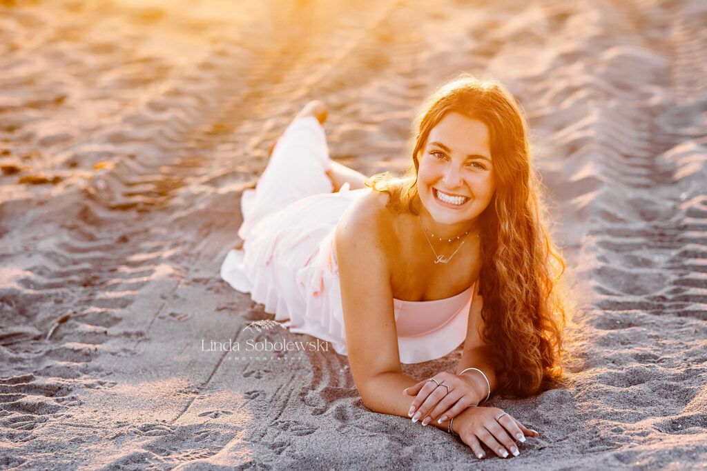 pretty girl in pink dress laying down in the sand, Old Saybrook and Westbrook senior photographer