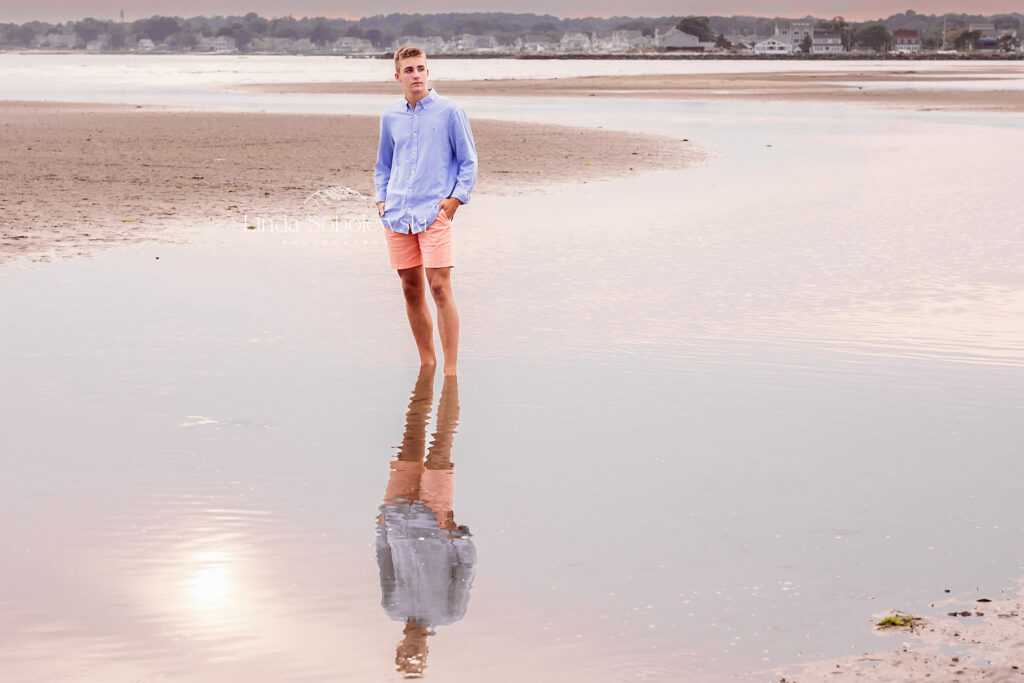 boy in blue shirt walking in the water, CT shoreline senior photographer