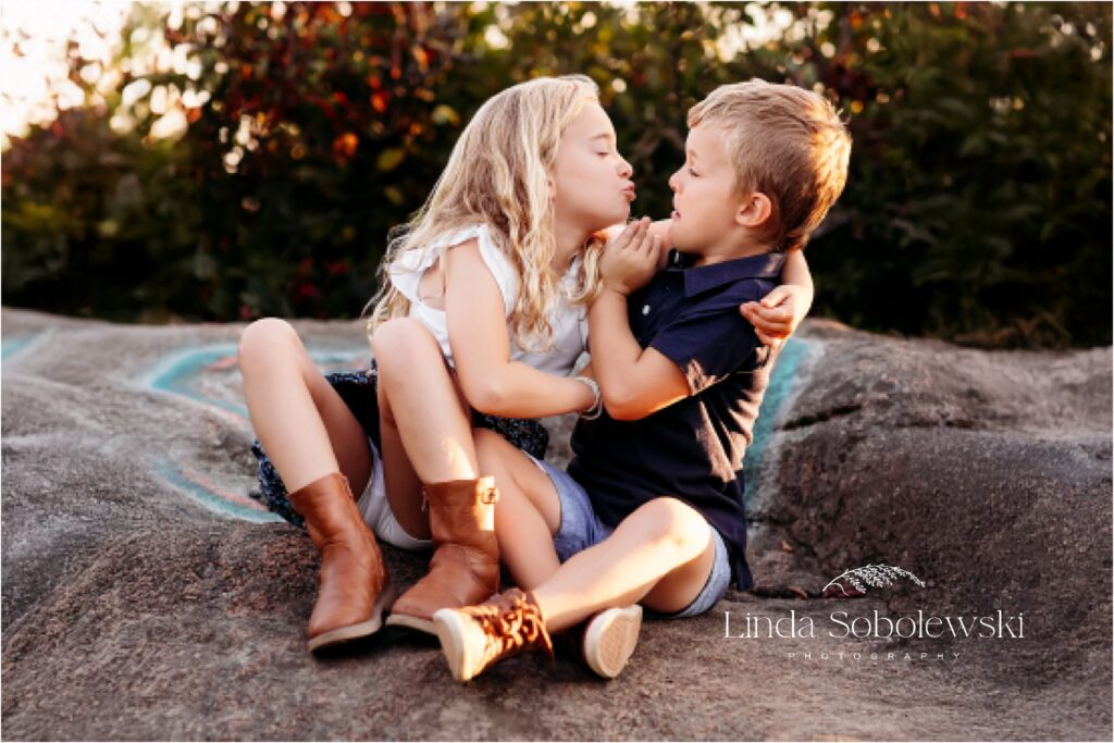 sister trying to kiss her little brother, CT family photographer, 2024 Session Superlatives