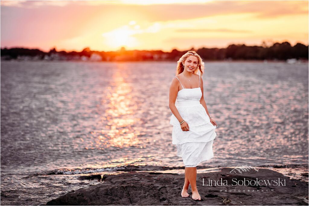 girl in long white dress with a beautiful sunset behind her, Madison CT photographer