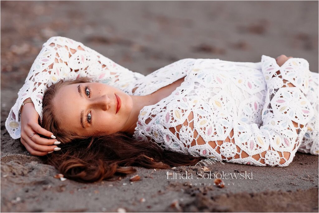 teenage girl in white dress laying down at the beach, Gymnastics Senior Session in CT