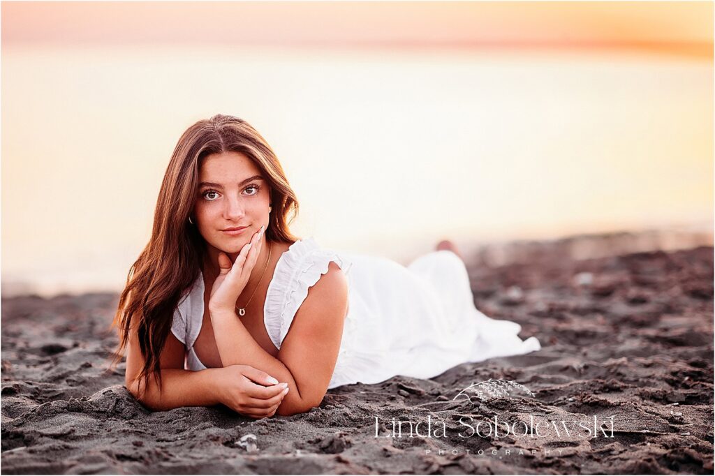 girl with long black hair laying on the beach, Senior Photos By The Water