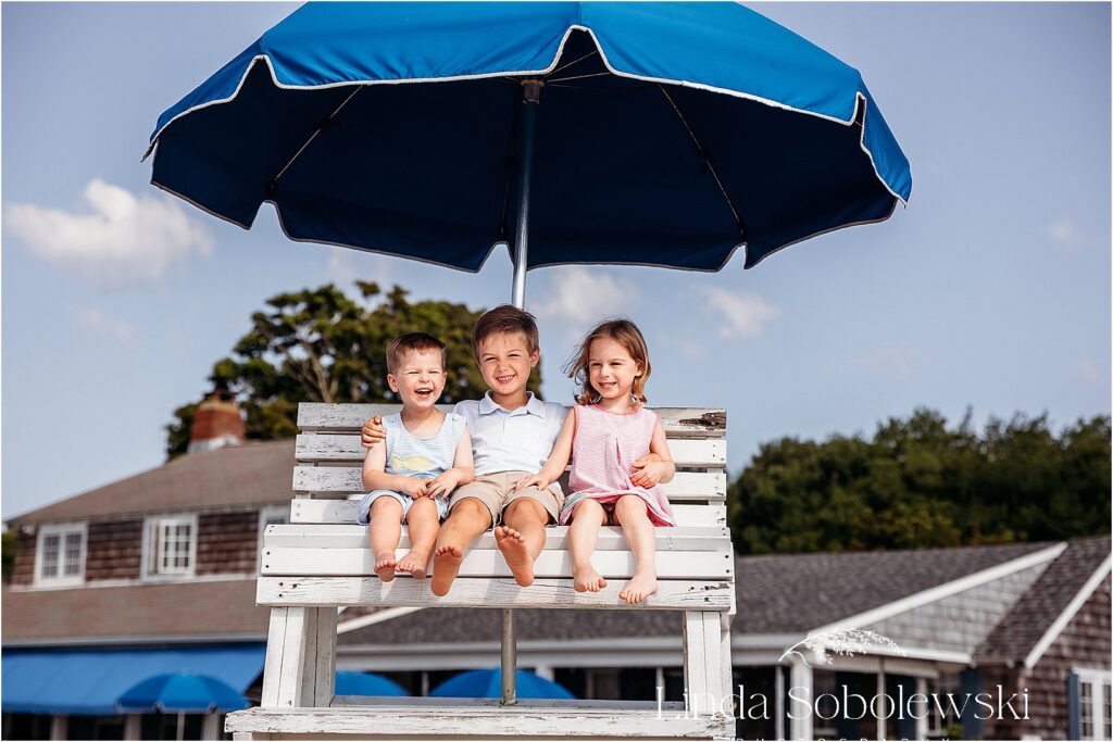 cousins sitting on a lifeguard chair for their Multi-generational family photo shoot at the beach