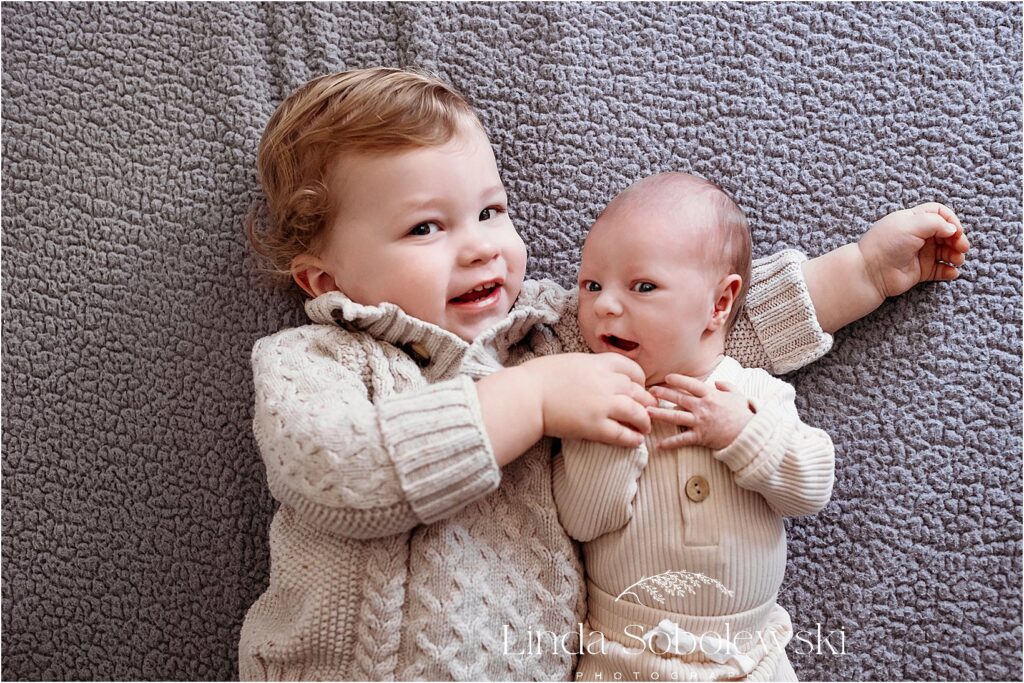 baby boy and his brother laying on bed, Guilford CT newborn photographer