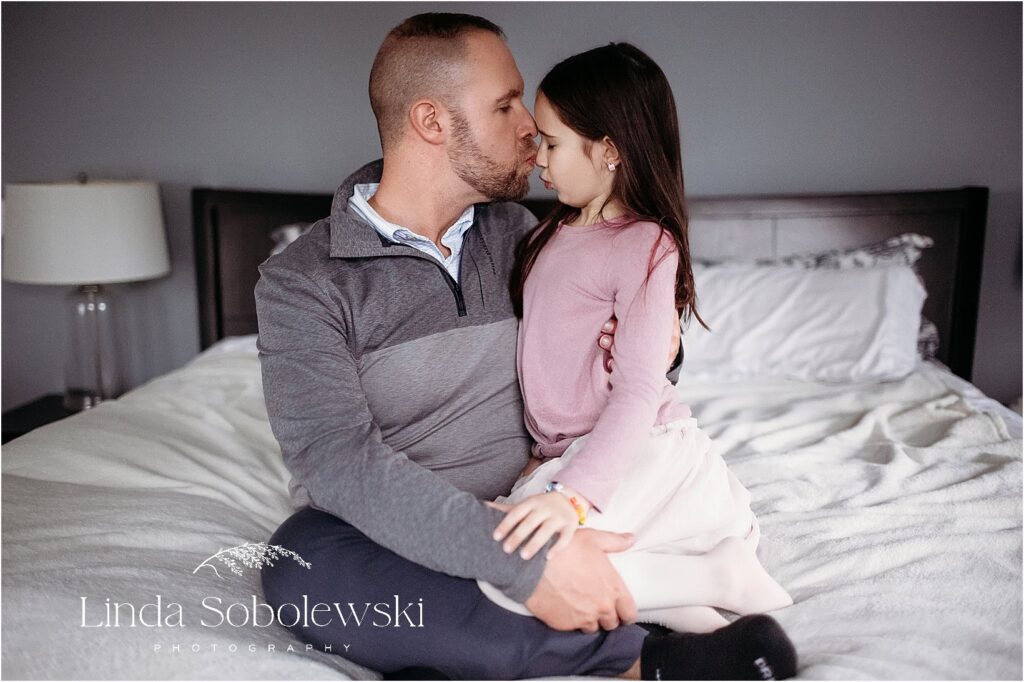 A father lovingly embraces his young daughter during a lifestyle newborn photography session in Connecticut.