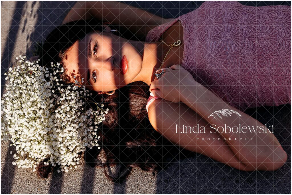 Creative senior portrait with dramatic shadows and baby's breath in dark flowing hair