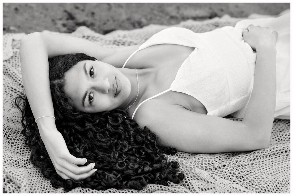 Black and white senior portrait of girl with curly hair on beach blanket, CT shoreline senior photographer