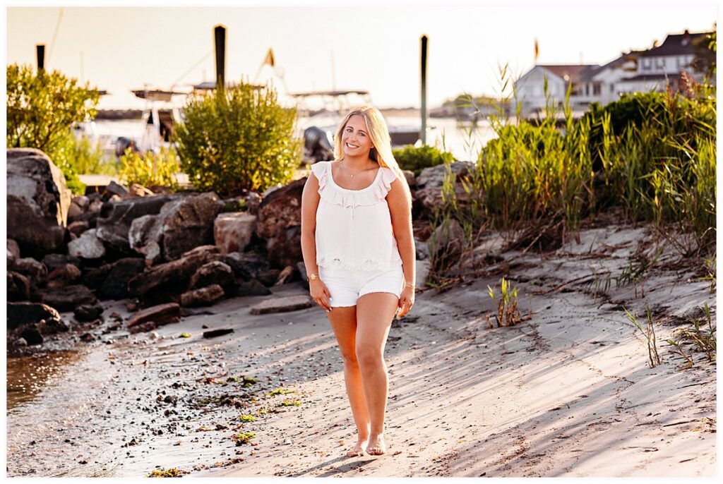 Elle walking barefoot along the sandy waterfront near a marina in Old Saybrook, Connecticut.